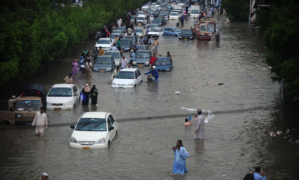 Commuters are seen on a flooded street following rains in Karachi on September 10, 2011. Six people including two women and a minor were electrocuted and more than two dozens injured in different parts of the city as heavy downpour lashed the metropolis afternoon, paralysing the communication and power supply network as more than 100 feeders of Karachi Electric Supply Company (KESC) tripped off the system.  (AFP)