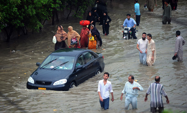 Commuters cross a flooded street following rains in Karachi on September 10, 2011. Six people including two women and a minor were electrocuted and more than two dozens injured in different parts of the city as heavy downpour lashed the metropolis afternoon, paralysing the communication and power supply network as more than 100 feeders of Karachi Electric Supply Company (KESC) tripped off the system.  (AFP)