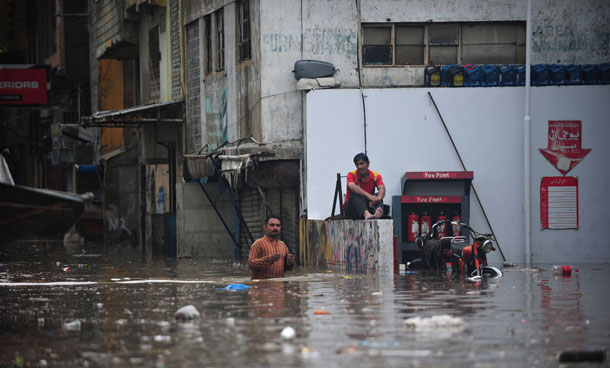 Pakistani filling station workers stand in a flooded area following rains in Karachi on September 10, 2011. Six people including two women and a minor were electrocuted and more than two dozens injured in different parts of the city as heavy downpour lashed the metropolis afternoon, paralysing the communication and power supply network as more than 100 feeders of Karachi Electric Supply Company tripped off the system. (AFP)