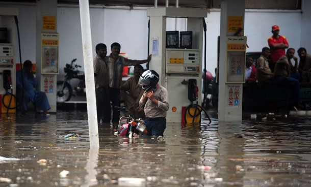 Pakistani filling station workers and a motorcyclist stand in a flooded area following rains in Karachi on September 10, 2011. Six people including two women and a minor were electrocuted and more than two dozens injured in different parts of the city as heavy downpour lashed the metropolis afternoon, paralysing the communication and power supply network as more than 100 feeders of Karachi Electric Supply Company (KESC) tripped off the system. (AFP)