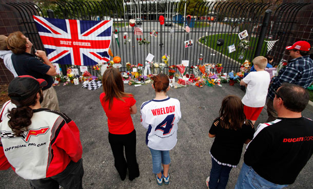 Kelley Bennett, left center, and Deana Klatcs, right center, look over items left at a memorial at the main gate at Indianapolis Motor Speedway for race driver Dan Wheldon in Indianapolis, Monday, Oct 17, 2011. Wheldon, a two-time Indianapolis 500 champion, died Sunday after a massive, fiery wreck at the IndyCar Series' Las Vegas Indy 300 auto race. (AP)