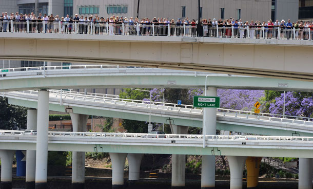 Residents line the Riverside freeway to see Britain's Queen Elizabeth II as she passes on the catamaran 'Pure Adrenalin' during the royal boat tour along the Brisbane River on Oct 24, 2011. Tens of thousands of well-wishers packed the banks of the Brisbane River.  (AFP)