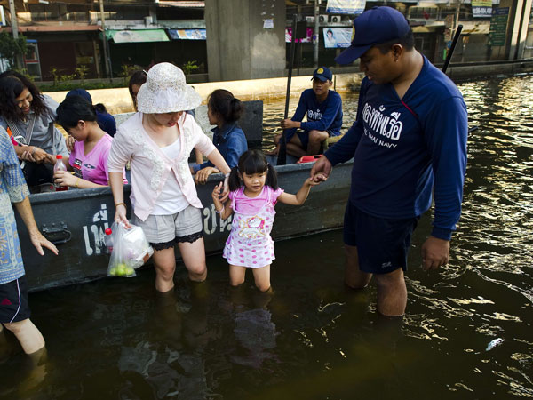 A girl is helped by a Royal Thai navy rescuer (R) and her mother (C) to get out of a boat in the flood waters on a street near the Chao Praya river in Bangkok on November 6, 2011. (AFP)