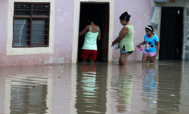 People enter a flooded house in Cali December 5, 2011. At least 96 people have died as a result of heavy rains, authorities said. Colombia's weather office expects La Nina-related downpours to continue at least until the end of the first quarter of next year. (REUTERS)