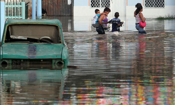 Residents walk past a car in a flooded street in Cali December 5, 2011. At least 96 people have died as a result of heavy rains, authorities said. Colombia's weather office expects La Nina-related downpours to continue at least until the end of the first quarter of next year. (REUTERS)