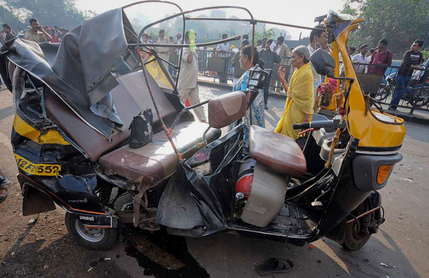 People walk past a damaged auto rickshaw at an accident site in Pune, about 190km (118 miles) from Mumbai. A government bus driver sped through the streets of the city on Wednesday smashing his empty bus into dozens of vehicles, killing nine people and injuring 27, police said. (REUTERS)