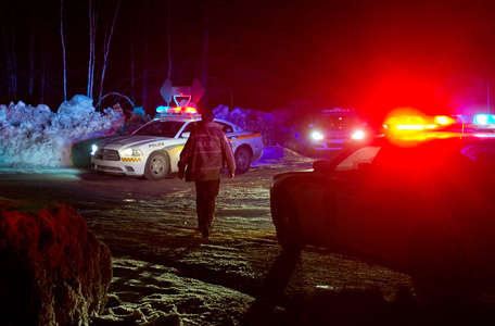 Police vehicles block a road just outside the town of Chertsey, Quebec, Sunday, March 17, 2013, during a search for escaped prisoners. A dramatic daylight jailbreak involving two Quebec inmates climbing a rope into a hovering helicopter swiftly escalated into a large police operation Sunday night in which at least one escapee was tracked down hours after he fled. (AP)