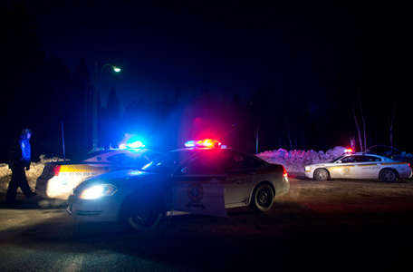 Police vehicles block a road just outside the town of Chertsey, Quebec, Sunday, March 17, 2013, during a search for escaped prisoners. A dramatic daylight jailbreak involving two Quebec inmates climbing a rope into a hovering helicopter swiftly escalated into a large police operation Sunday night in which at least one escapee was tracked down hours after he fled. (AP)