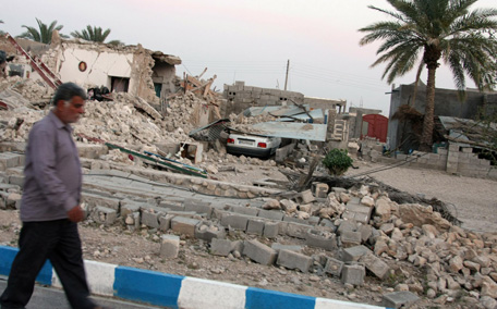 An Iranian man walks past the ruins of a destroyed house in the town of Shonbeh, southeast of Bushehr. (AFP)