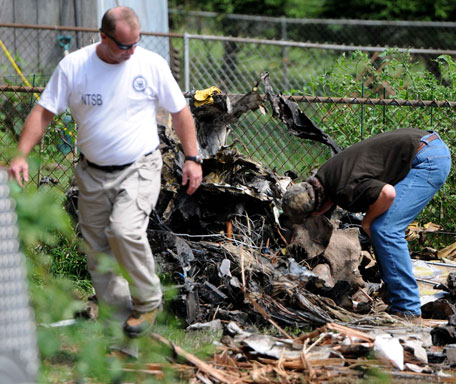 Officials inspect the debris on Saturday, Aug. 10, 2013 after a small plane, piloted by Bill Henningsgaard, crashed into two homes Friday in East Haven, Conn. Four people were killed in the incident. (AP)