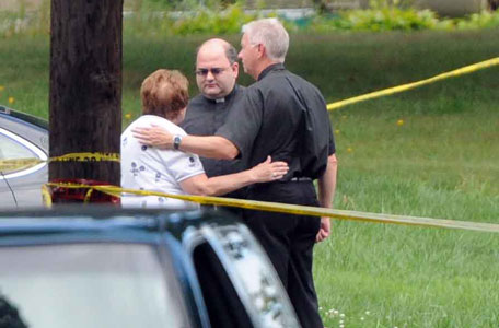 Priests talk with a neighbor on Saturday, Aug. 10, 2013 near the scene after a plane, piloted by Bill Henningsgaard, crashed into two homes Friday in East Haven, Conn. Four people were killed in the incident. (AP)