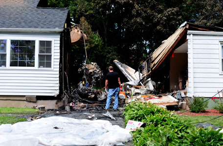 Officials inspect the debris on Saturday, Aug. 10, 2013 after a small plane, piloted by Bill Henningsgaard, crashed into two homes Friday in East Haven, Conn. Four people were killed in the incident. (AP)