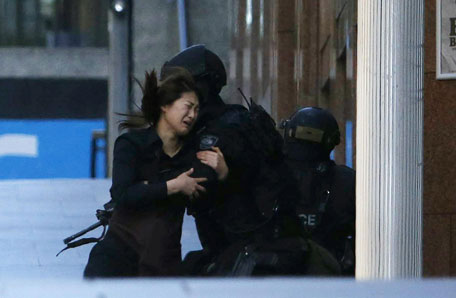 A hostage runs towards a police officer outside Lindt cafe, where other hostages are being held, in Martin Place in central Sydney December 15, 2014. (AFP)