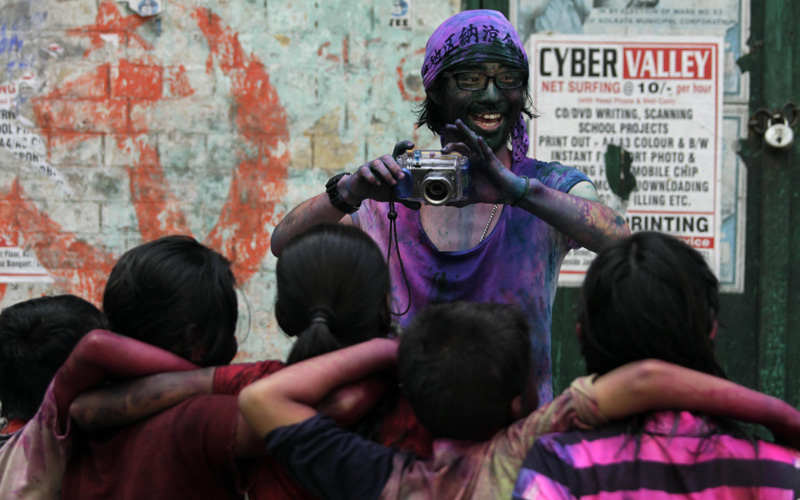 A tourist smeared with colors shoots photographs of children celebrating "Holi," the Indian festival of colors, in Calcutta. (AP)